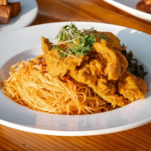 Majani Soulful Vegan Cuisine's vegan spaghetti with orange sauce, topped with fried vegan chicken and microgreens.