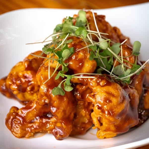 Majani Soulful Vegan Cuisine's vegan wings, coated in a rich brown sauce and garnished with fresh microgreens.
